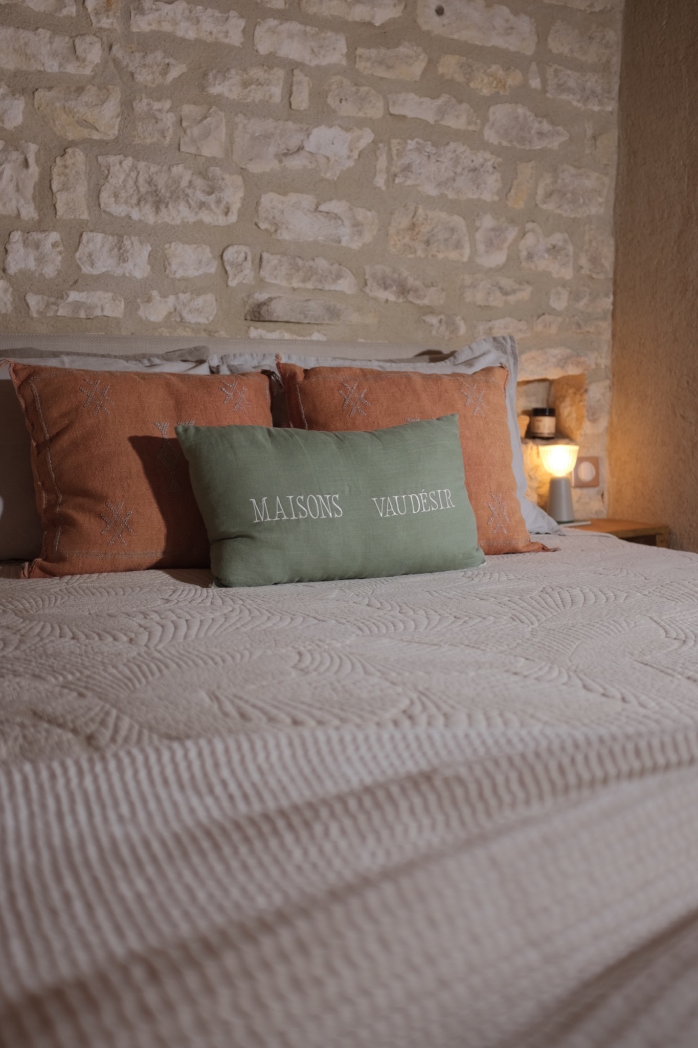 Kipli bed with terracotta cushions against a bare limestone wall