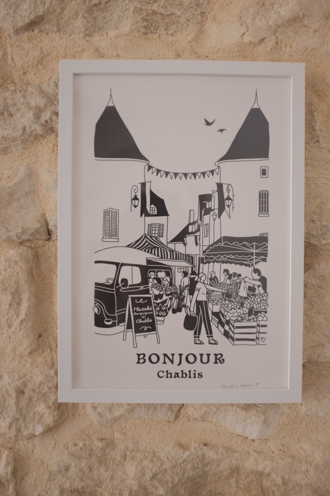 Framed Bonjour Chablis market print on a limestone wall
