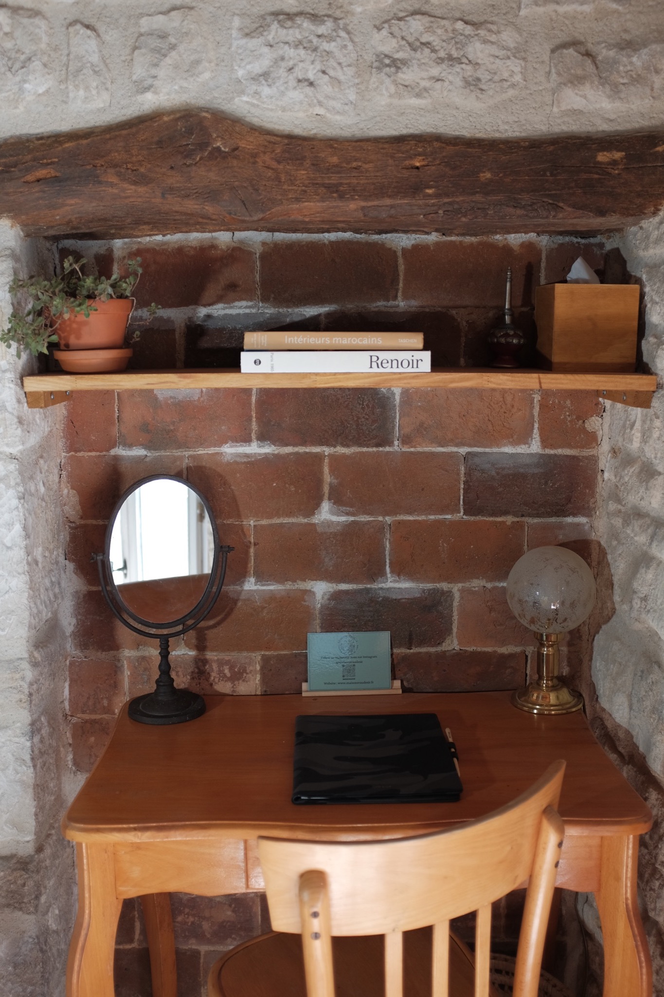 Small wooden desk set into a brick alcove with a tilting mirror