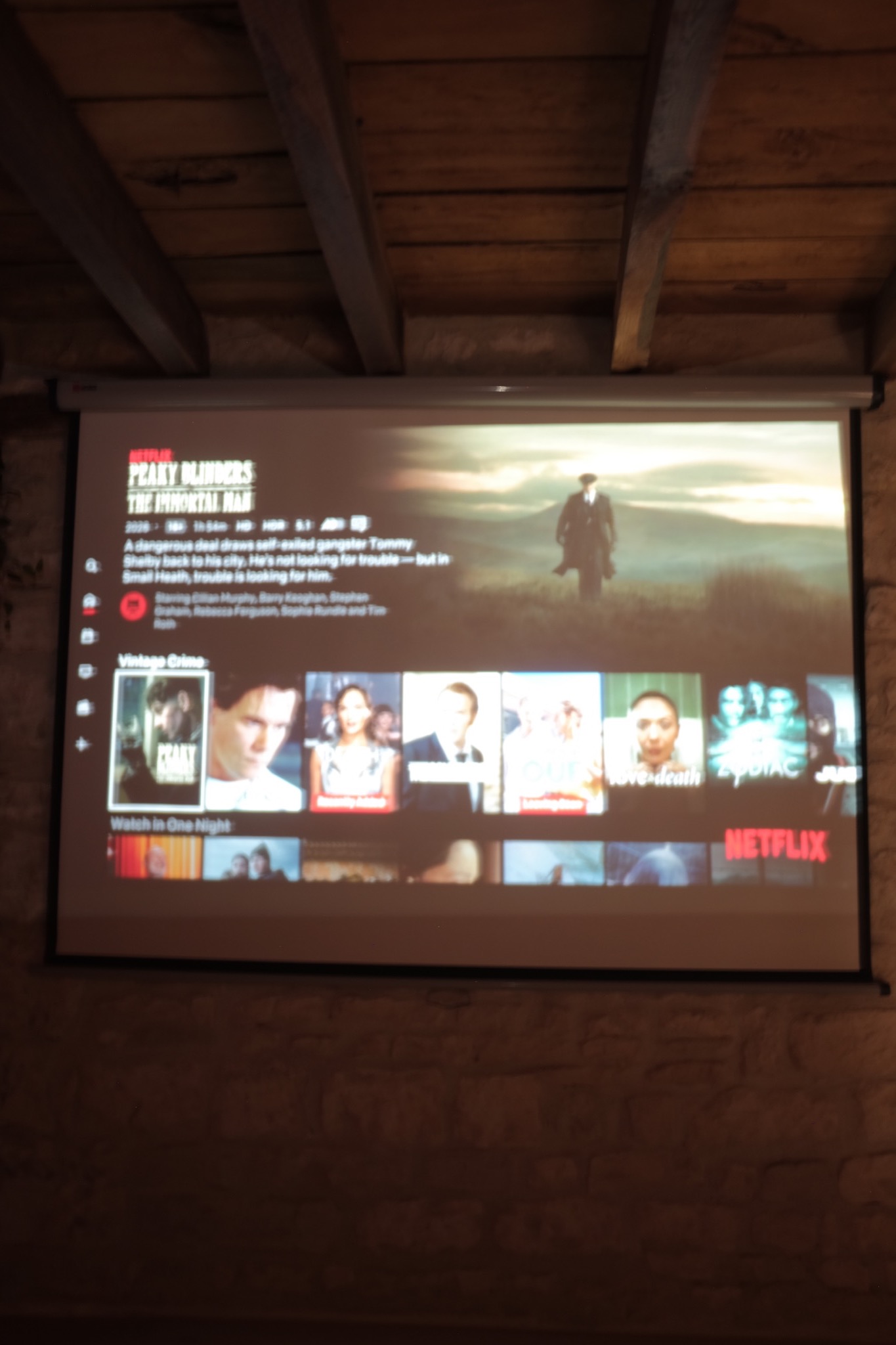 Pull-down projection screen at the foot of the bed under the beams